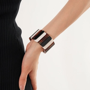 Detail of geometric resin cuff bracelet with black white and amber panels on wrist