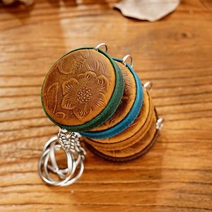 Close-up of handmade leather keychains with vintage floral embossing on wooden surface
