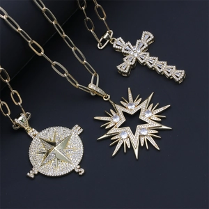 Three gold layered necklaces featuring cross, compass star, and star pendants on paperclip chains