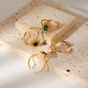 Detail of four gold adjustable rings with colorful oval gemstones and zircon sunflowers