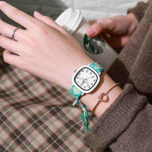 Detail shot of a minimalist square quartz watch with a green fabric strap on wrist