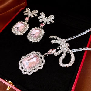Close-up of pink crystal bow necklace and earrings set displayed in a red jewelry box