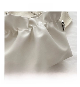 Close-up of white leather pleats and precision stitching on the French bucket bag