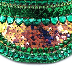 Macro shot of green sequins and heart-shaped gemstone details on festive party hat