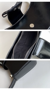 Close-up of black patent leather baguette bag showing glossy texture and magnetic closure