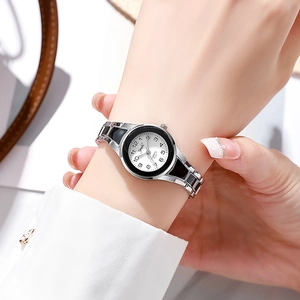 Close-up of silver and black quartz watch with white round dial on woman wrist