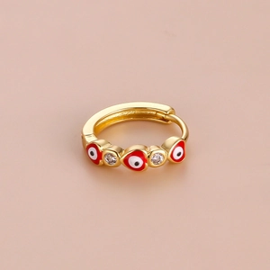 Detail of a gold hoop earring with red enamel heart and sparkling zircon stone