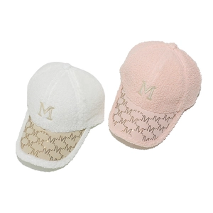 Close-up of white and pink faux fur baseball caps with rhinestone M logo embroidery