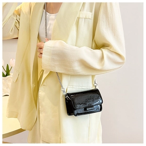 Close-up of black glossy croc-effect mini square bag with silver metal chain strap