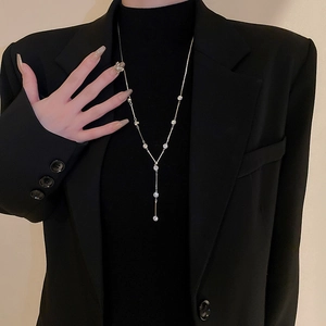 Detail of silver Y-shaped tassel necklace with sparkling crystal inlay on black sweater