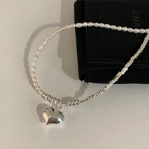 Elegant pearl and silver heart pendant necklace for women on minimalist grey background