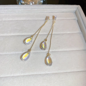 Close-up of golden tassel earrings with aurora teardrop charms on a velvet tray