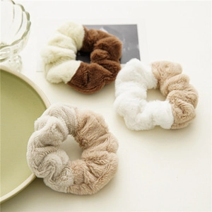 Dettaglio degli elastici per capelli in peluche bicolore marrone e beige su un tavolo