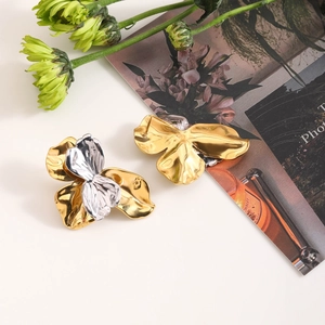 Macro detail of large 3D metallic flower earrings in gold and silver finish