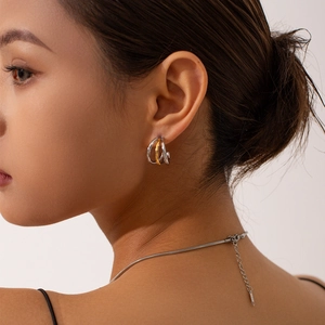 Gros plan de boucles d'oreilles créoles multicouches en or et argent sur un mannequin