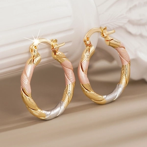 Detail of elegant triple-tone twisted hoop earrings with gold, rose gold and silver finish