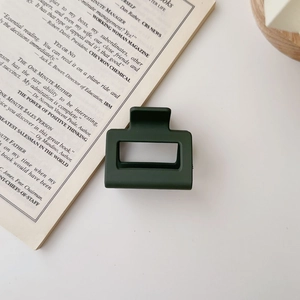 Detail of square hollow hair claw clip in matte dark green on a vintage book