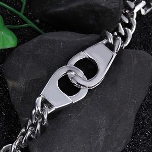 Detail of silver hip hop bracelet featuring handcuff design and thick cuban chain links