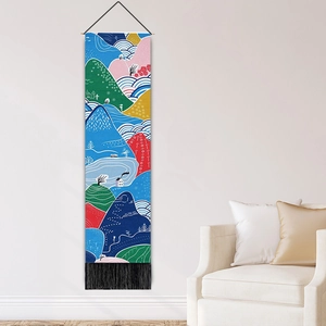 Modern landscape tapestry with colorful mountains and black tassels hanging on a white wall
