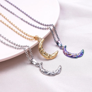 Hammered crescent moon necklaces in silver, gold, and rainbow finishes on ceramic tray