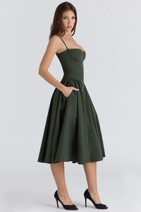 Detail of dark green midi dress featuring a corset bodice and practical side pockets