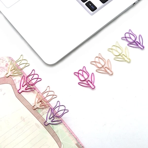 Macro shot of colorful tulip-shaped metal paperclips used as bookmarks on a notepad