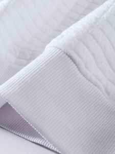 Detail of white ribbed cuff and quilted fabric texture on long sleeve sweatshirt