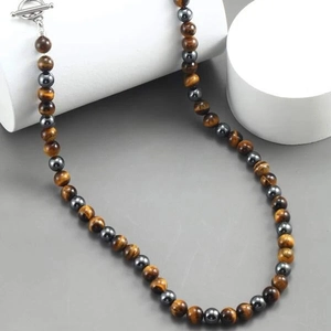 Macro detail of men's tiger eye and hematite beaded necklace with silver T-bar clasp closure