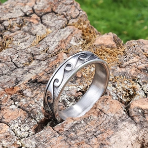 Minimalist stainless steel wave ring in silver finish placed on natural wood bark
