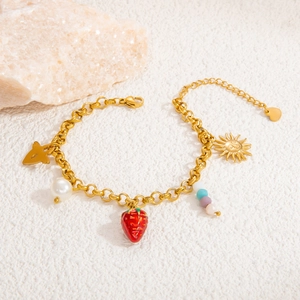 Detailed view of beaded bracelet with strawberry and sun charms on golden chain