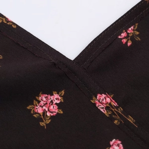 Détail du décolleté en V avec imprimé de roses roses sur une texture de tissu foncé