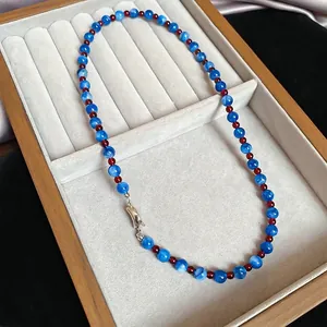 Blue jade beaded necklace with red accents and silver lobster clasp in a jewelry box