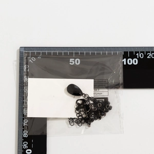 Close-up of a Gothic black teardrop pendant necklace next to a ruler for size reference
