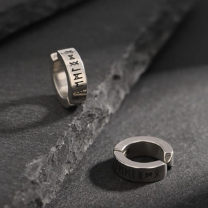 Macro shot of silver titanium steel ear cuff featuring Nordic rune engravings on stone