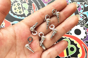 Macro detail of gold and silver microphone charms with inlaid zircons on palm