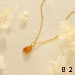 Detailed close-up of a 18K gold-plated teardrop necklace with an orange gemstone pendant