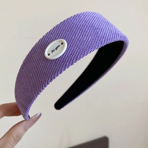 Détail d'un serre-tête large en velours violet avec étiquette Ai you et doublure