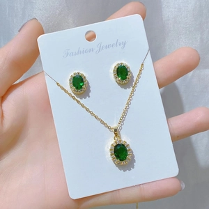 Detail of emerald oval jewelry set with necklace and earrings in gold finish