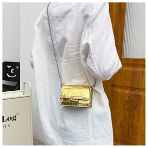Lifestyle shot of a mini gold crocodile texture chain bag worn as a crossbody
