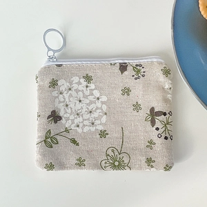 Close-up of floral cotton pouch with white zipper and metal ring on clean background