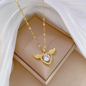 Gold winged heart necklace with sparkling crystal inlay displayed on white silk in box