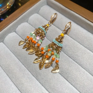 Macro shot of bohemian tassel earrings with turquoise beads and gold leaf pendants