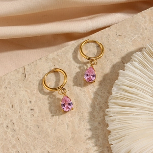 Detalle de pendientes de oro 18K con circonia rosa en forma de gota sobre seda y piedra