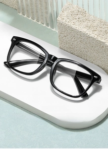 Detailed close-up of square black frame glasses with silver rivets on a display stand