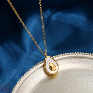 Macro view of a gold avocado pendant with shell inlay on a blue silk background