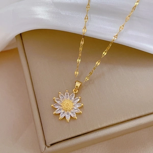 Luxury gold sunflower pendant necklace with white zirconia crystals on a jewelry box