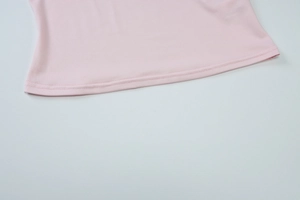 Détails du tissu en maille lisse et coutures précises sur le débardeur rose clair