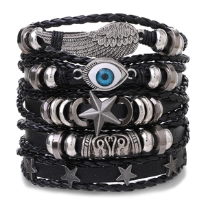 Detail of multi-layer leather bracelets with wing, blue eye, and star charms