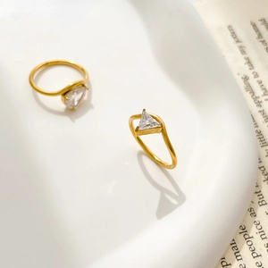 Detail of minimalist gold-plated rings featuring a triangular-cut zircon on slim bands