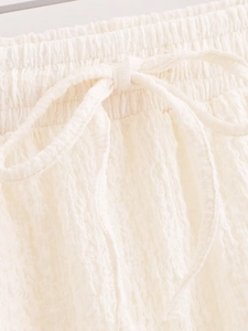 Detail view of off-white elastic waistband with drawstring and textured fabric detail